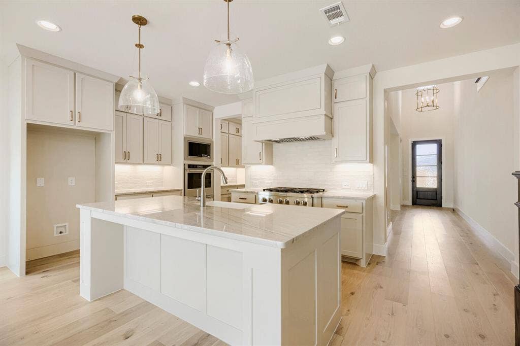 940 Heatherbrook Drive, Prosper, TX 75078 Bright kitchen featuring a substantial island with countertop, recessed lighting, double ovens, and a gas range