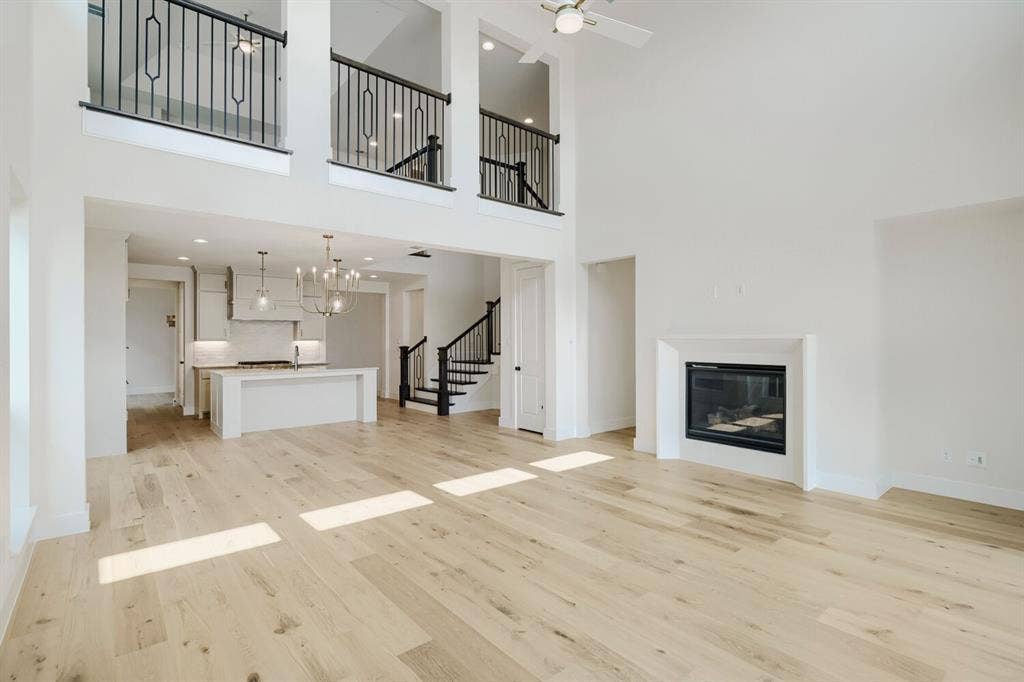 940 Heatherbrook Drive, Prosper, TX 75078 Expansive living area with high ceilings, wood-finish flooring, and a built-in fireplace