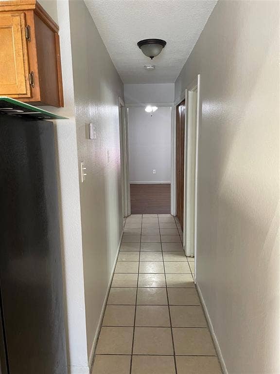 3441 Pewitt Drive, #43, Waco, TX 76706 Corridor featuring light tile patterned flooring and a textured ceiling