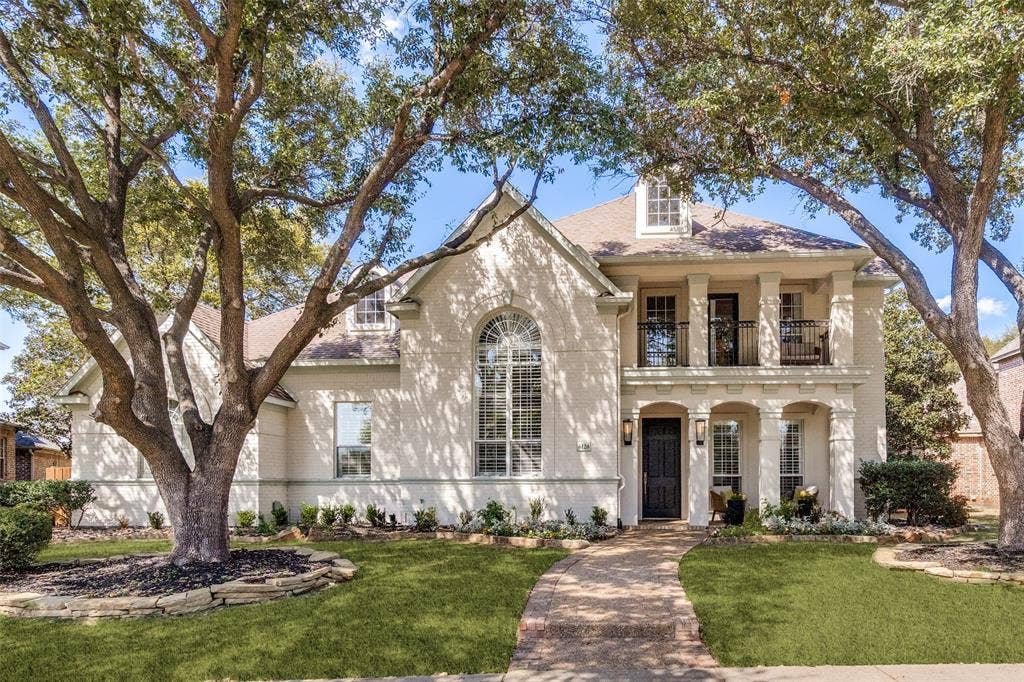 Stunning home with large covered porch, balcony and gorgeous oak trees.