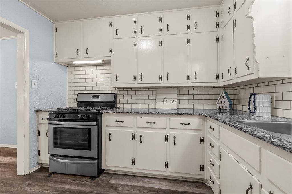 901 N Main Street, West, TX 76691 Kitchen featuring stainless steel gas range, dark stone counters, and white cabinets