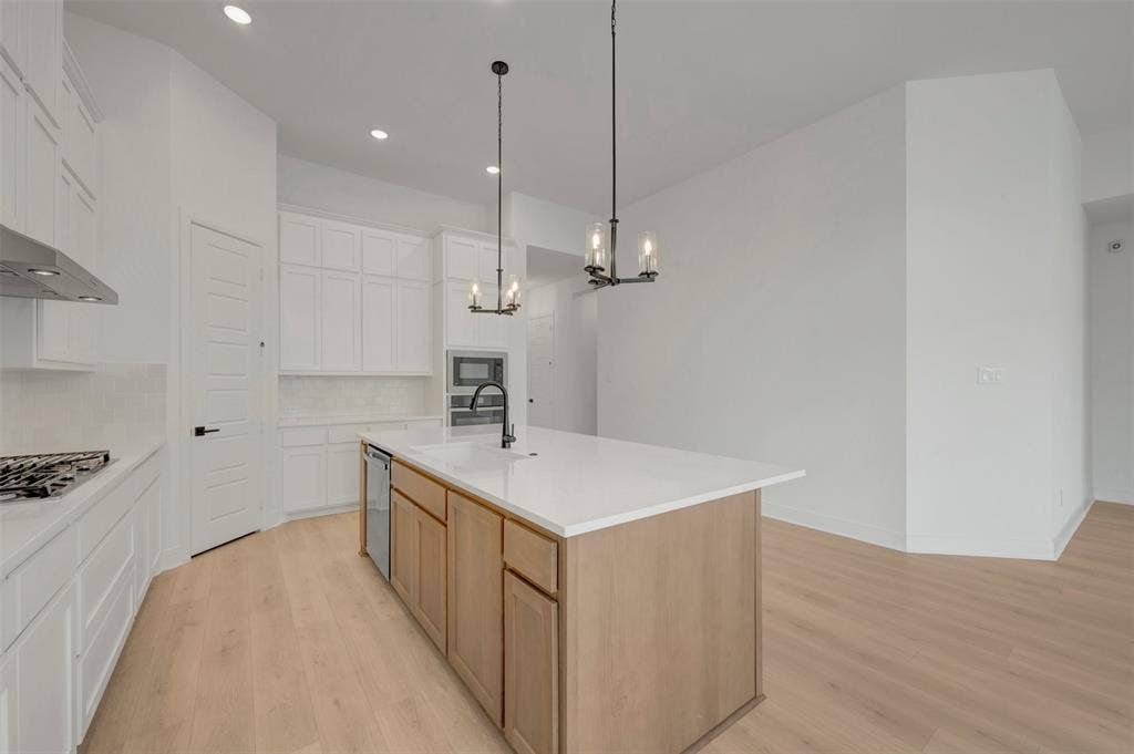 1709 Drover Street, Northlake, TX 76247 Modern kitchen featuring a light wood-finish flooring, white cabinetry, a large center island with a light-toned countertop, and recessed lighting