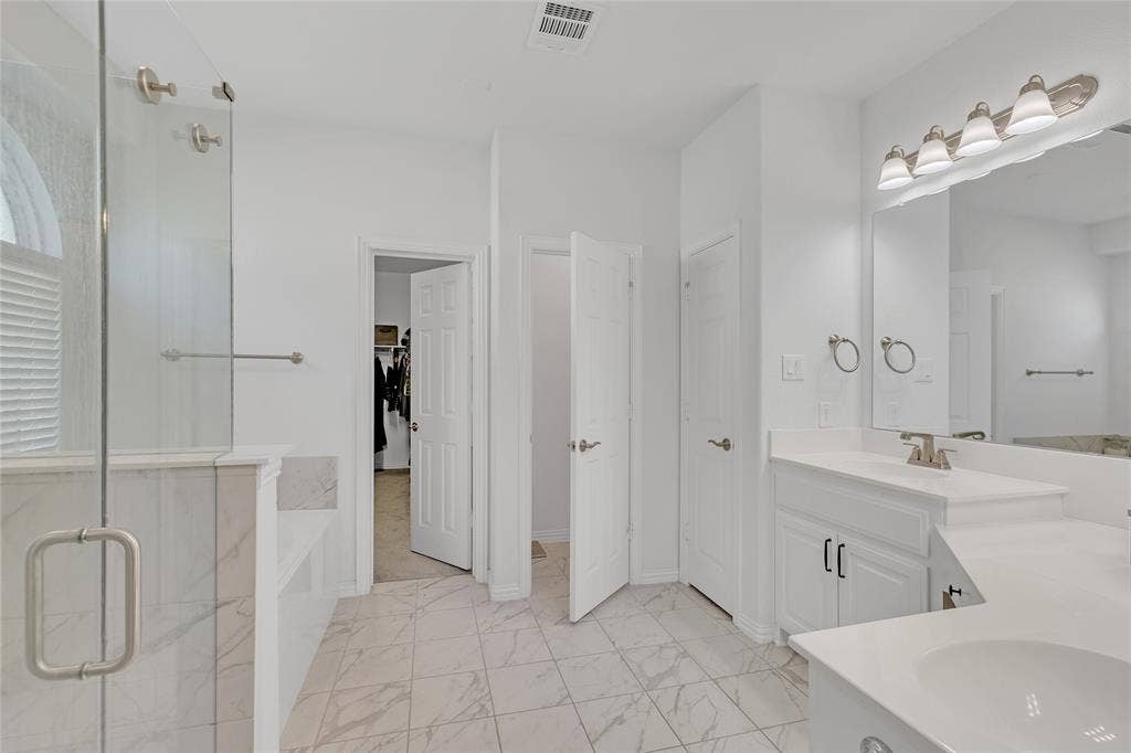 566 Long Meadow Drive, Haslet, TX 76052 Primary bath with dual sinks, a garden tub, and walk-in shower with glass surround. Door to toilet room, linen storage, and walk-in closet.