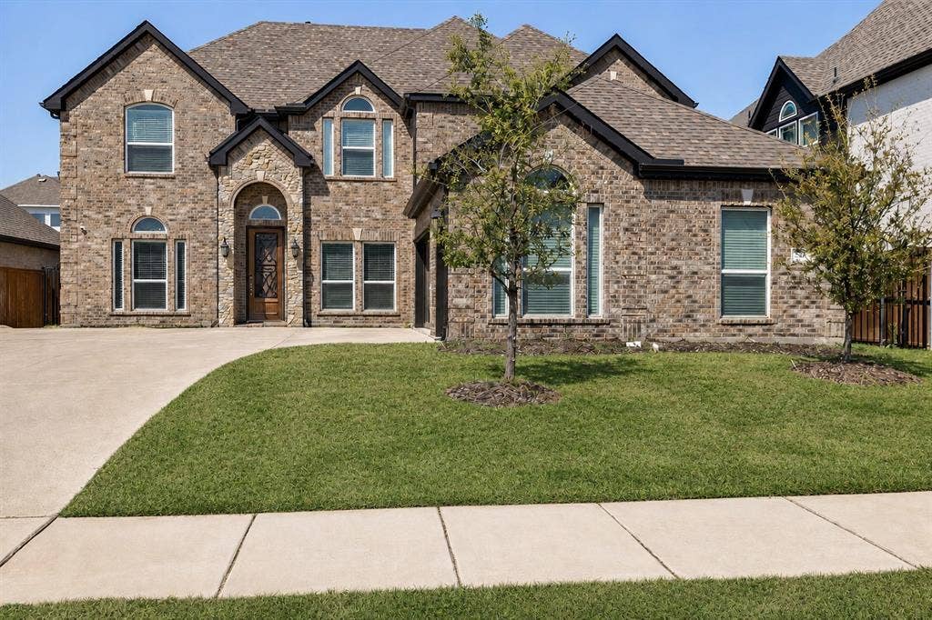 566 Long Meadow Drive, Haslet, TX 76052 Traditional brick-clad exterior featuring multiple gables and a prominent arched entry