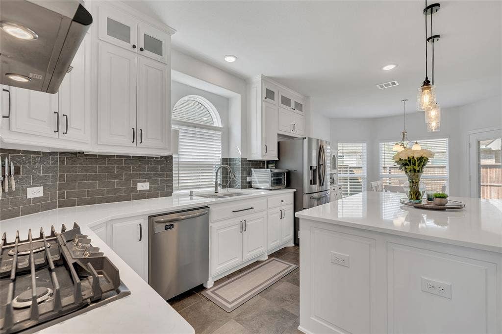 566 Long Meadow Drive, Haslet, TX 76052 Has cooktop with modern accents on the backsplash and carried floors throughout main areas on first floor.