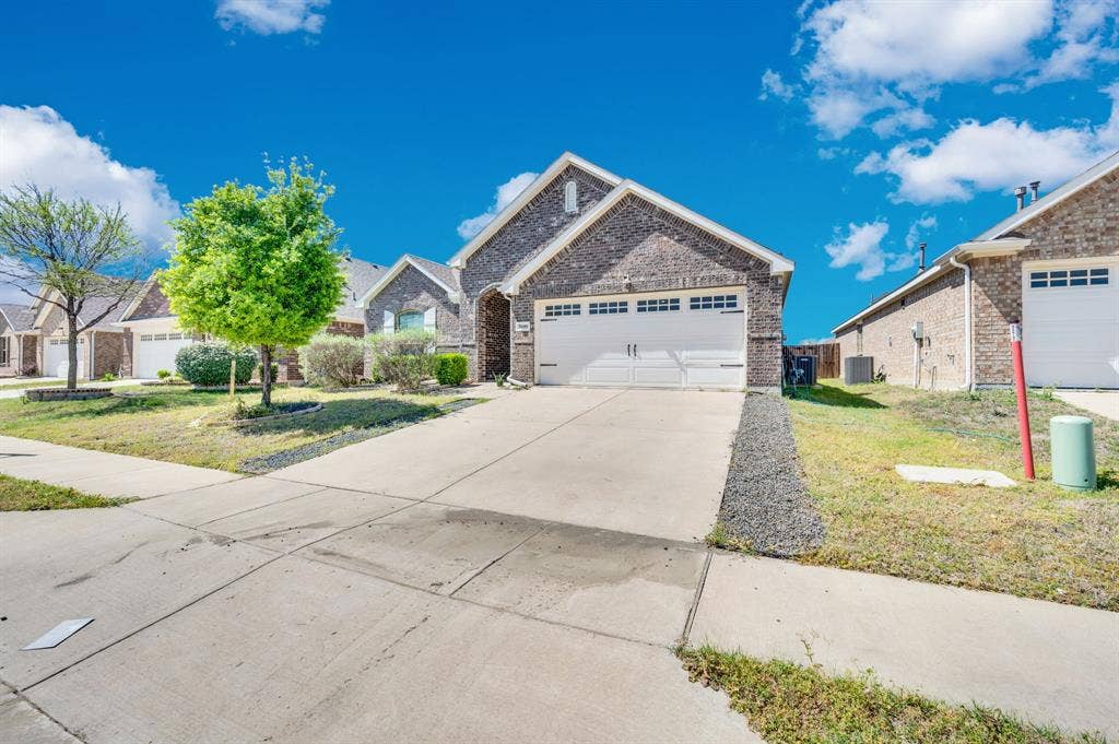 2609 Centurion Road, Glenn Heights, TX 75154 View of front of home with brick siding, an attached garage, concrete driveway, a front yard, and a residential view
