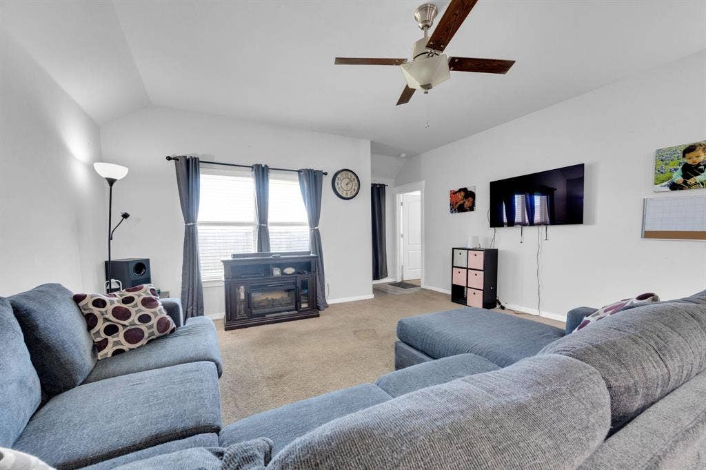 2609 Centurion Road, Glenn Heights, TX 75154 Carpeted living area with vaulted ceiling, a ceiling fan, and a glass covered fireplace