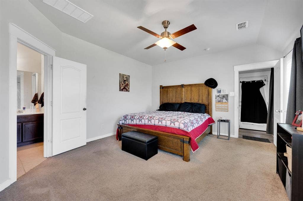 2609 Centurion Road, Glenn Heights, TX 75154 Bedroom with light colored carpet, lofted ceiling, a ceiling fan, and connected bathroom