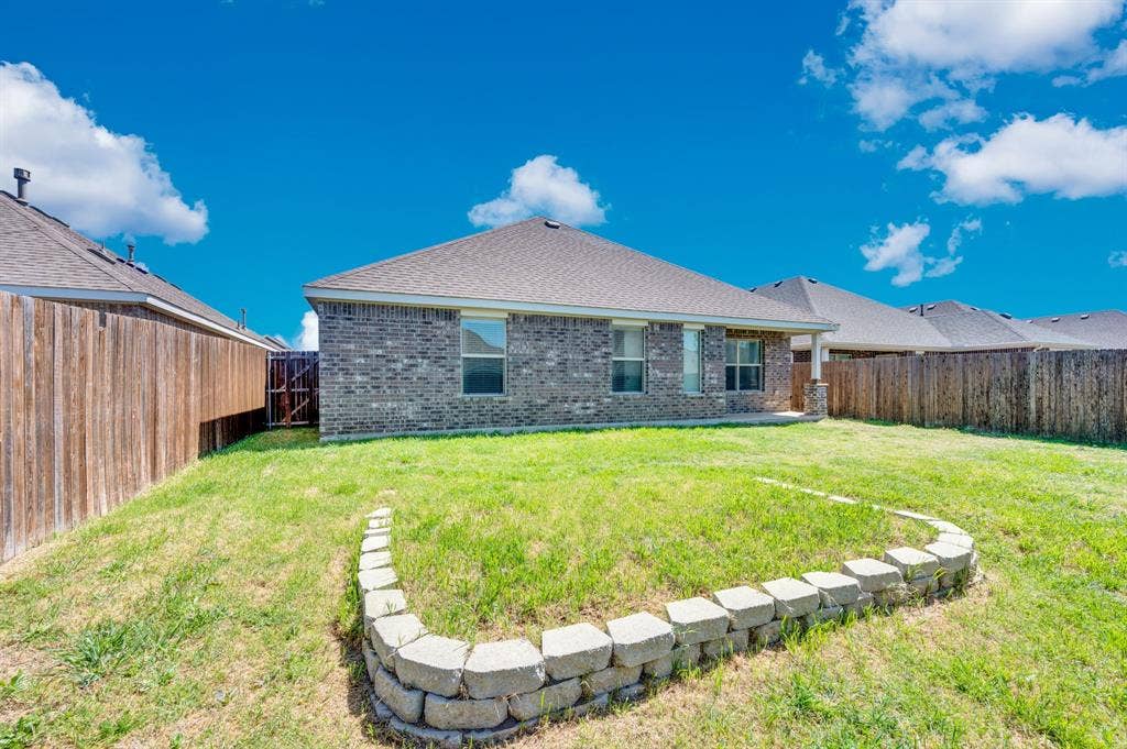 2609 Centurion Road, Glenn Heights, TX 75154 Rear view of house featuring brick siding, a patio area, a fenced backyard, and roof with shingles