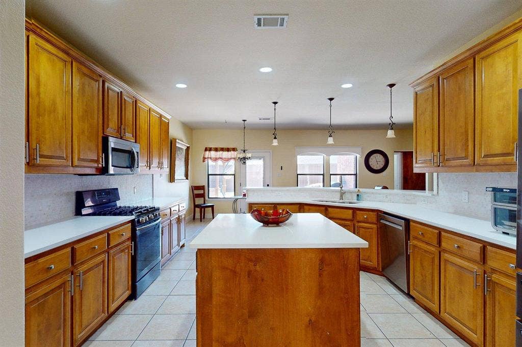 349 Creekside Trail, Argyle, TX 76226 Kitchen with decorative backsplash, wood finish cabinets, stainless steel appliances, and a kitchen island