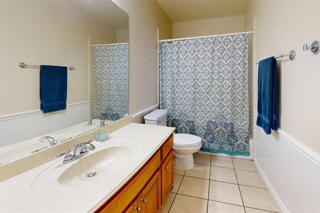 349 Creekside Trail, Argyle, TX 76226 Full bathroom featuring a wainscoted wall, vanity, light tile patterned floors, shower / bath combination with curtain, and a decorative wall