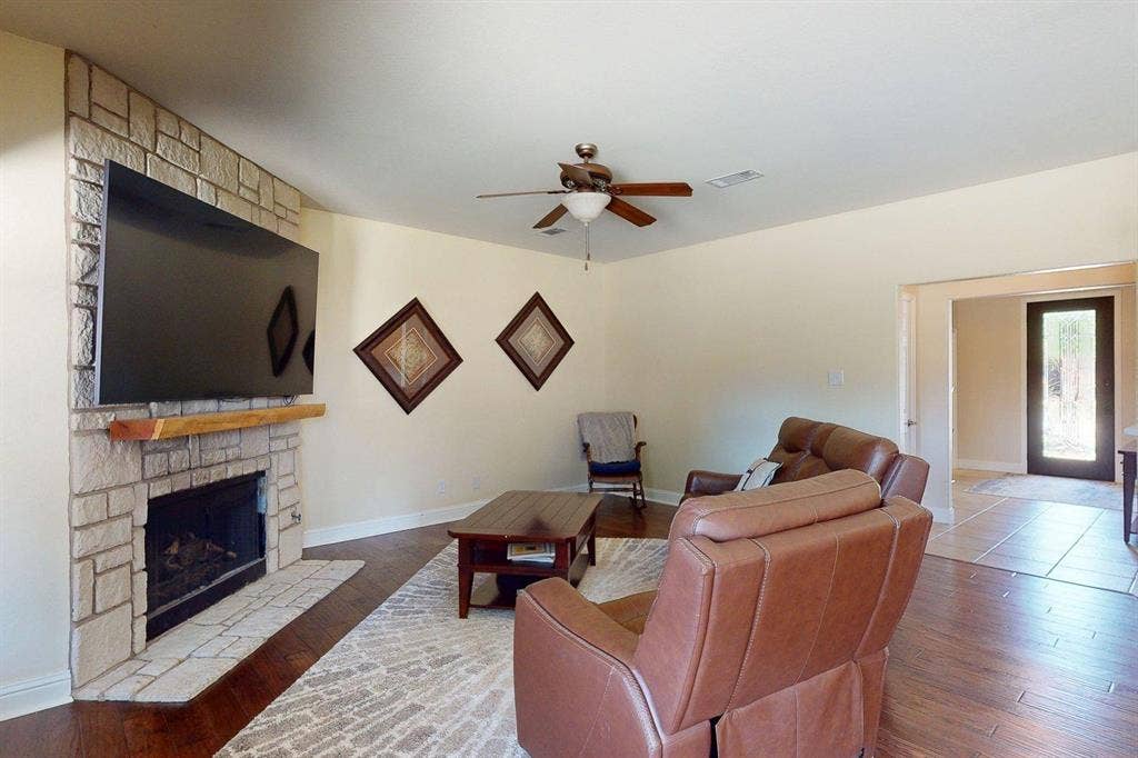 349 Creekside Trail, Argyle, TX 76226 Living room featuring a stone fireplace, wood finished floors, and ceiling fan
