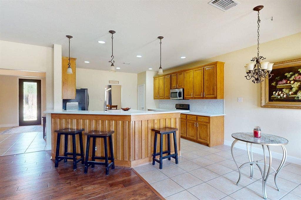 349 Creekside Trail, Argyle, TX 76226 Kitchen featuring a breakfast bar, wood finish cabinetry, light countertops, a peninsula, and light tile patterned floors