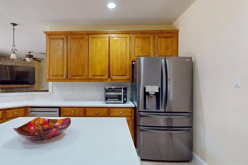 349 Creekside Trail, Argyle, TX 76226 Kitchen with stainless steel appliances, wood finish cabinets, light countertops, decorative backsplash, and pendant lighting