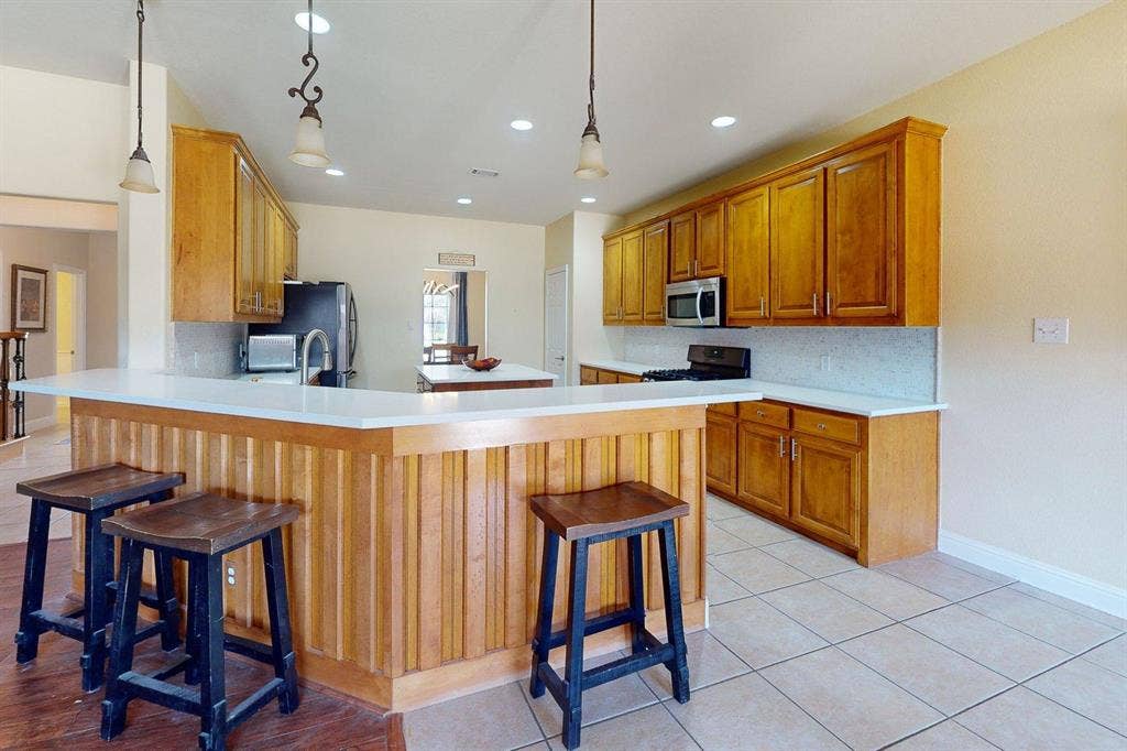 349 Creekside Trail, Argyle, TX 76226 Kitchen with a kitchen breakfast bar, light countertops, backsplash, and wood finish cabinets