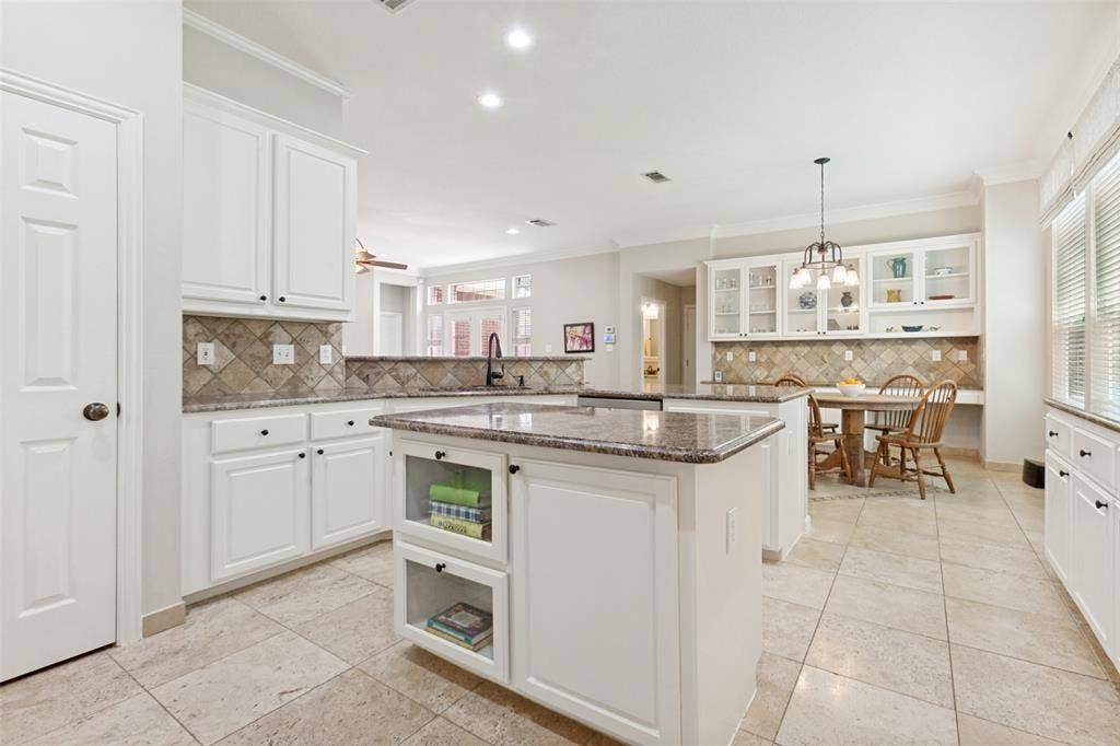 2632 Barrington Drive, Plano, TX 75093 Spacious kitchen featuring an island with built-in shelving, white cabinetry, granite countertops, and a tiled backsplash