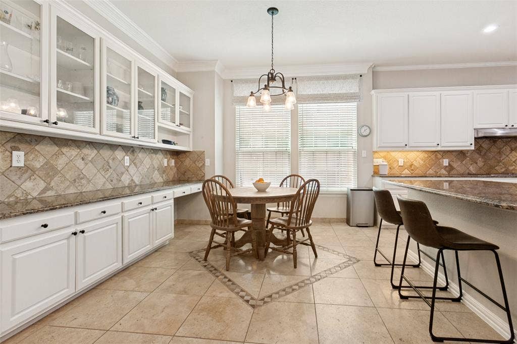 2632 Barrington Drive, Plano, TX 75093 Kitchen & Breakfast Room with white cabinetry, stone tile flooring, granite countertops, and upper and lower cabinets.