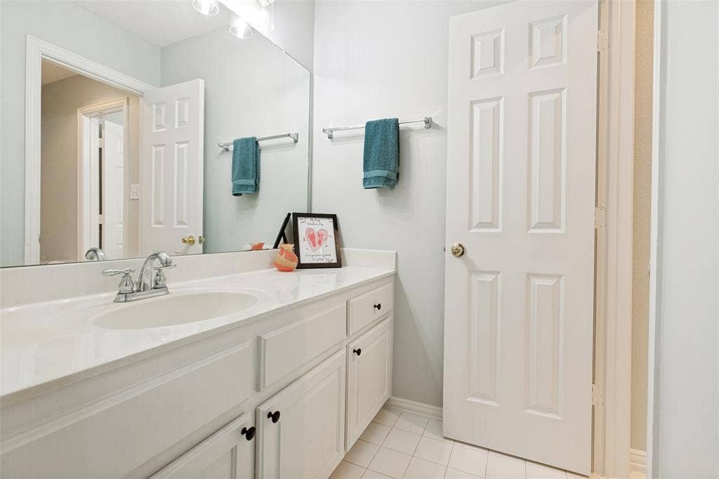 2632 Barrington Drive, Plano, TX 75093 Jack and Jill bathroom with white vanity, a built-in sink, chrome faucet and updated light fixture