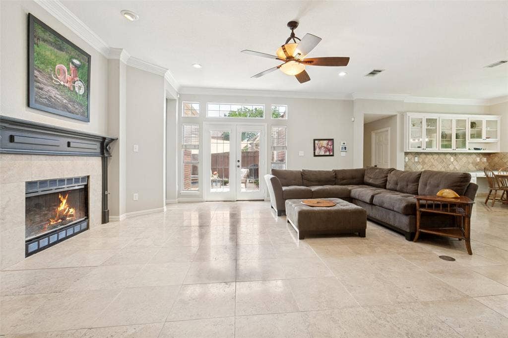 2632 Barrington Drive, Plano, TX 75093 Spacious living area featuring light-toned tile flooring, a fireplace with a dark mantel, and multiple windows
