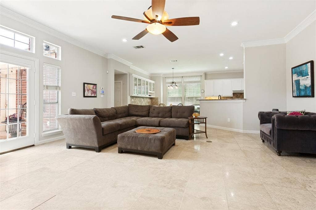 2632 Barrington Drive, Plano, TX 75093 Expansive living area featuring light-toned tile flooring, a ceiling fan with integrated lighting, recessed lighting, crown molding, and tall windows with transom details