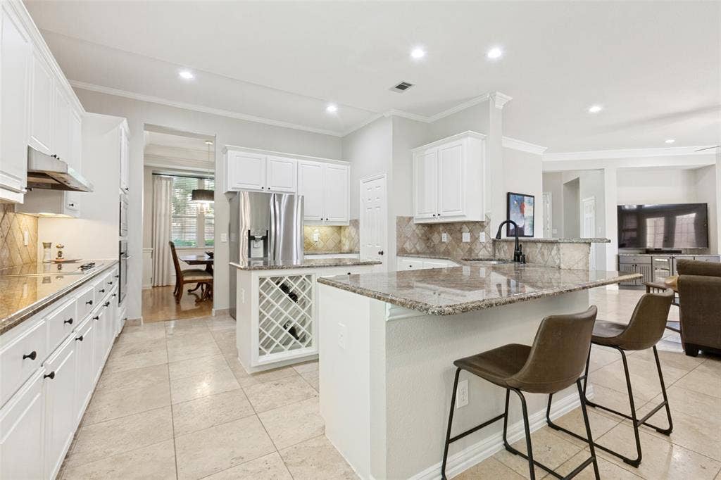 2632 Barrington Drive, Plano, TX 75093 Kitchen featuring white cabinetry, granite countertops, stainless steel appliances, a built-in wine rack, and tile flooring