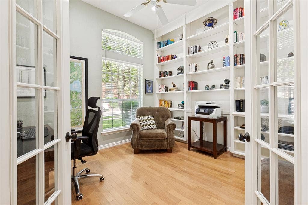 2632 Barrington Drive, Plano, TX 75093 French doors open to a versatile room featuring extensive built-in shelving, wood-finish flooring, and multiple windows