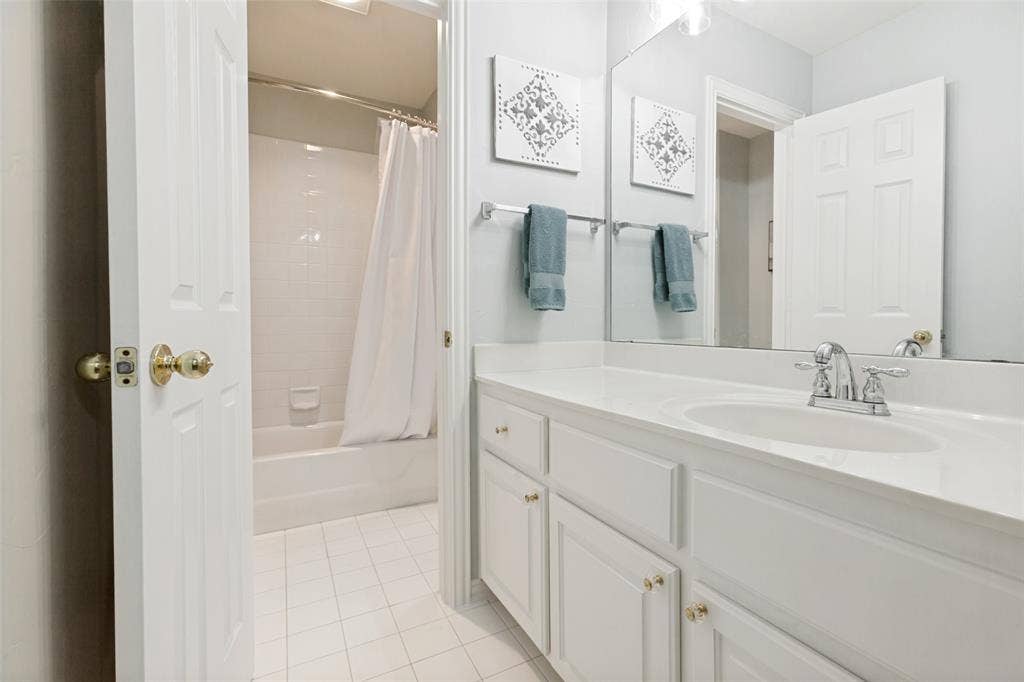 2632 Barrington Drive, Plano, TX 75093 Jack and Jill bathroom featuring a single vanity with an integrated sink, polished chrome faucet, a large wall-mounted mirror and updated light fixture