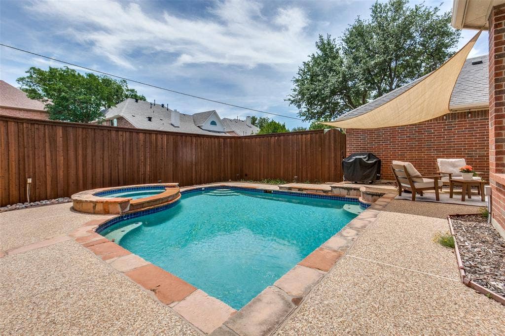 2632 Barrington Drive, Plano, TX 75093 Backyard boasts a Gunite pool with integrated spa, exposed aggregate concrete decking, and board-on-board fence