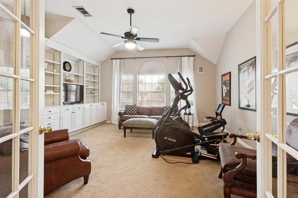 2632 Barrington Drive, Plano, TX 75093 French doors opening to a versatile room featuring extensive built-in cabinetry, arched windows, vaulted ceilings, and a ceiling fan