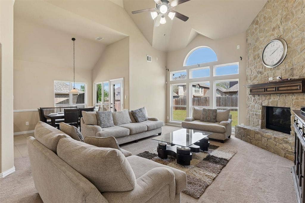 2446 Old Stables Drive, Celina, TX 75009 Living room featuring light carpet, a stone fireplace, ceiling fan, and vaulted ceiling