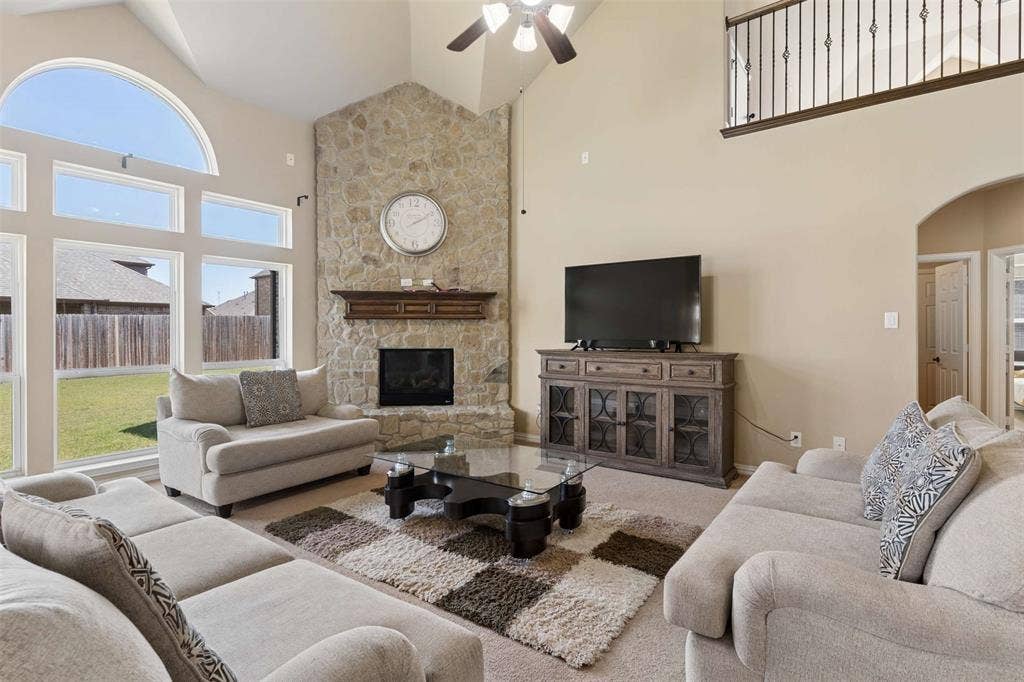 2446 Old Stables Drive, Celina, TX 75009 Carpeted living area featuring arched walkways, lofted ceiling, a fireplace, and ceiling fan