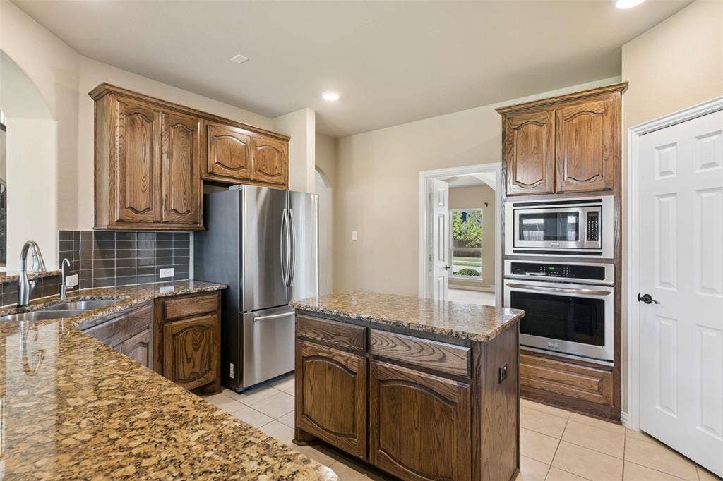 2446 Old Stables Drive, Celina, TX 75009 Kitchen featuring a center island, stainless steel appliances, dark stone countertops, light tile patterned floors, and recessed lighting