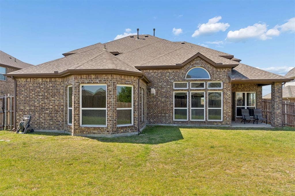 2446 Old Stables Drive, Celina, TX 75009 Rear view of property with a fenced backyard, brick siding, roof with shingles, and a patio area