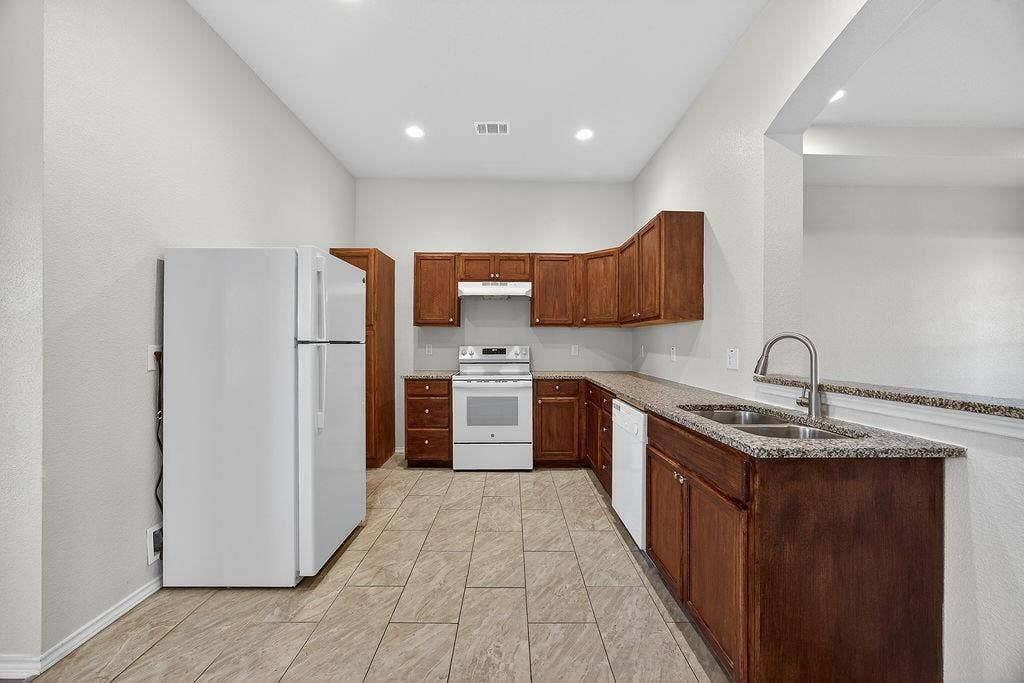 625 Green Mound Drive, Glenn Heights, TX 75154 Kitchen featuring white appliances, light stone counters, wood finish cabinets, and recessed lighting