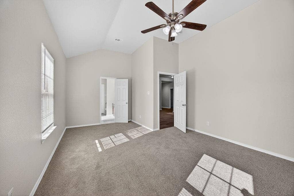 625 Green Mound Drive, Glenn Heights, TX 75154 Unfurnished bedroom featuring light colored carpet, vaulted ceiling, and a ceiling fan