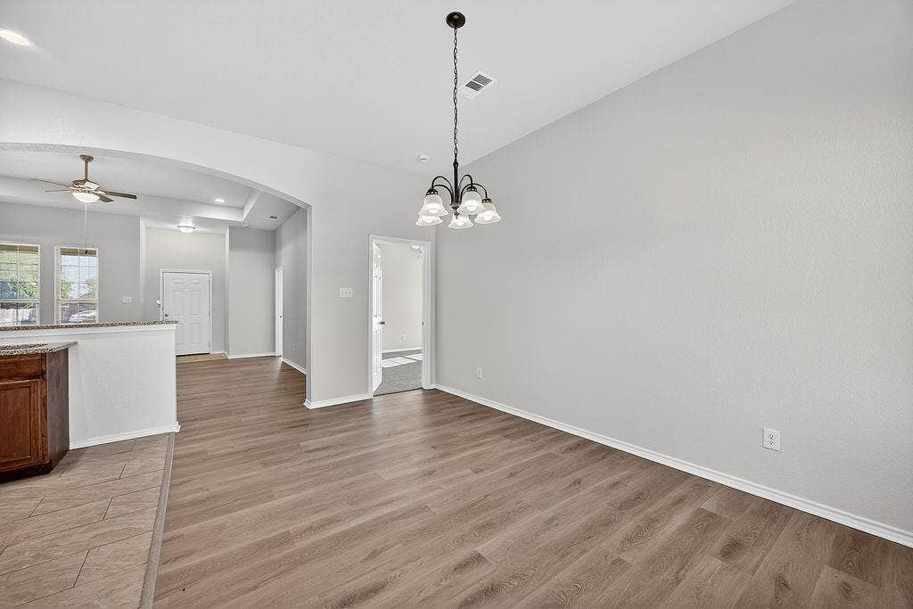 625 Green Mound Drive, Glenn Heights, TX 75154 Unfurnished dining area with ceiling fan, dark wood finished floors, suspended lighting, and arched walkways