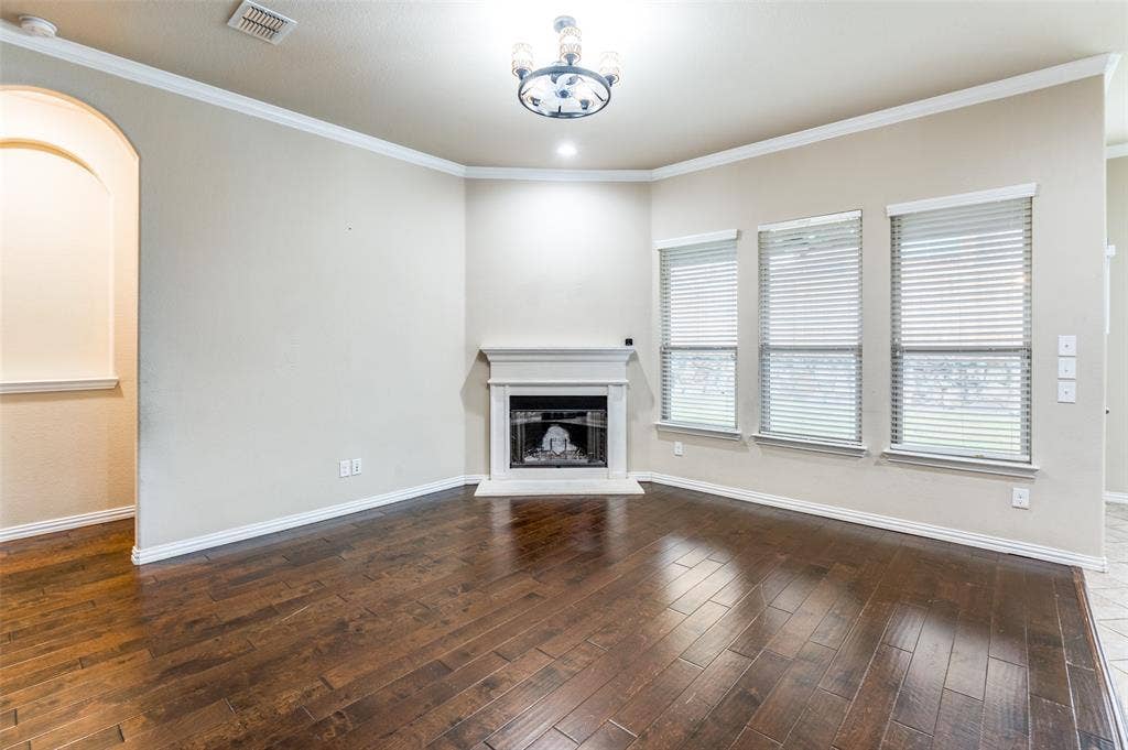 16425 Toledo Bend Court, Prosper, TX 75078 Unfurnished living room with a fireplace with raised hearth, dark wood finished floors, and ornamental molding