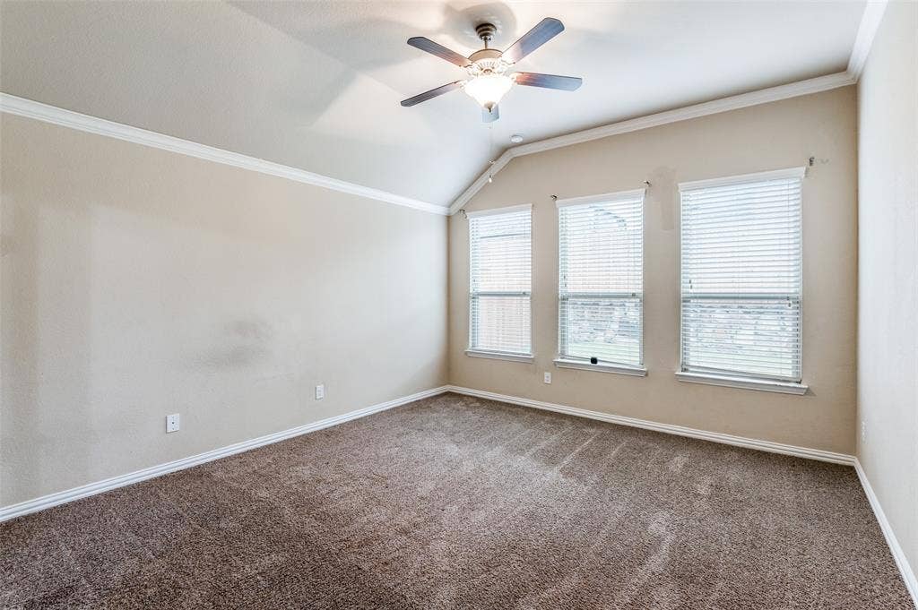 16425 Toledo Bend Court, Prosper, TX 75078 Empty room with crown molding, vaulted ceiling, dark carpet, and ceiling fan