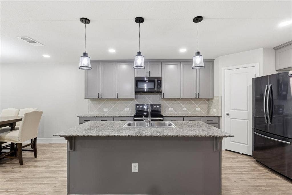 1212 Mount Olive Lane, Forney, TX 75126 Kitchen island featuring a double basin sink and a granite countertop