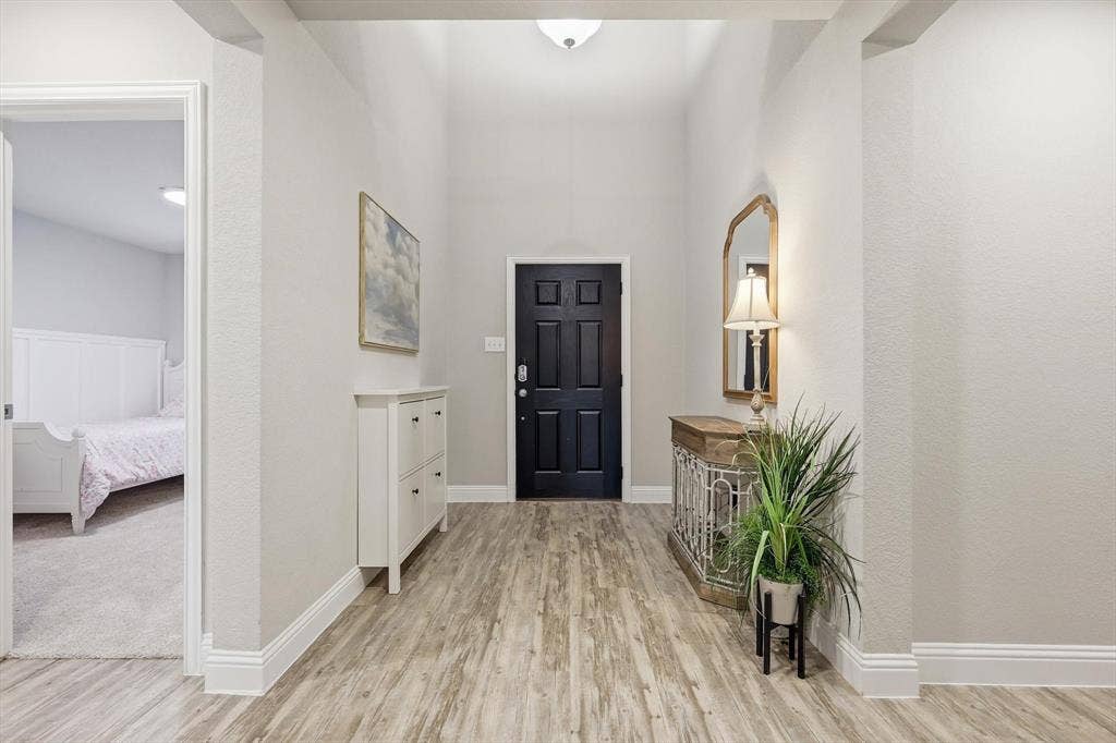 1212 Mount Olive Lane, Forney, TX 75126 Entryway featuring wood-finish flooring, a paneled black door, vaulted ceiling, and neutral wall tones