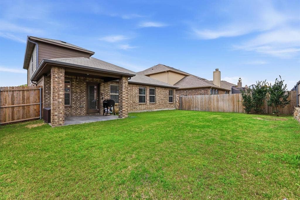 1212 Mount Olive Lane, Forney, TX 75126 Expansive backyard featuring a covered patio with brick columns and a substantial lawn space.