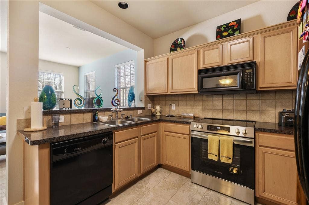 3025 Stone Forest Circle, McKinney, TX 75070 Kitchen featuring black appliances, dark countertops, a peninsula, and decorative backsplash