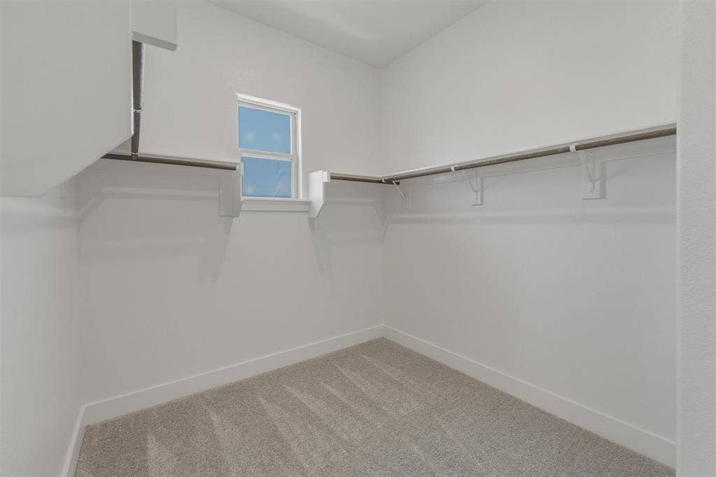2408 Quartz Street, Krum, TX 76249 Walk-in closet featuring light-toned carpeting, white walls, and a window providing natural illumination