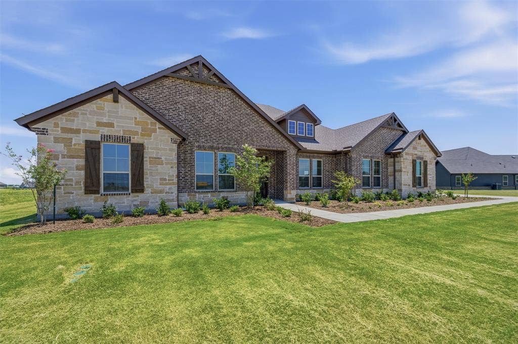 2408 Quartz Street, Krum, TX 76249 Stone and brick exterior featuring gabled rooflines, dark wood shutters, a dormer window, and an extended concrete walkway
