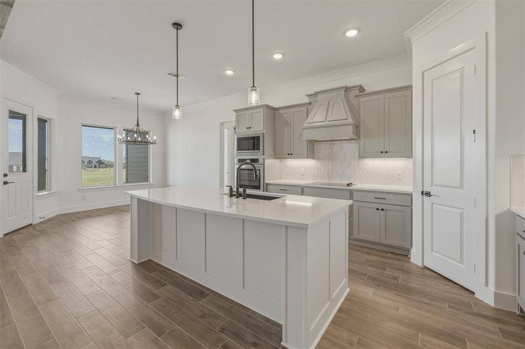2408 Quartz Street, Krum, TX 76249 Kitchen featuring a white island with pendant lighting, light gray cabinetry, white countertops, and wood-finish flooring