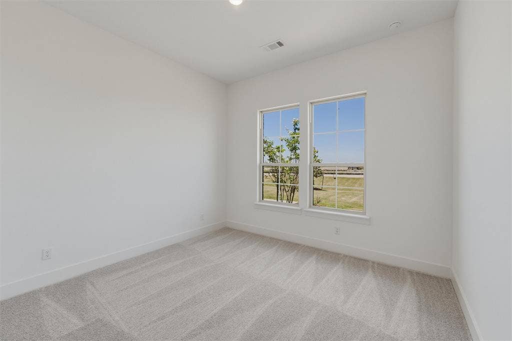 2408 Quartz Street, Krum, TX 76249 Bright interior space featuring two large windows, light gray patterned carpet, white baseboards, and neutral wall tones