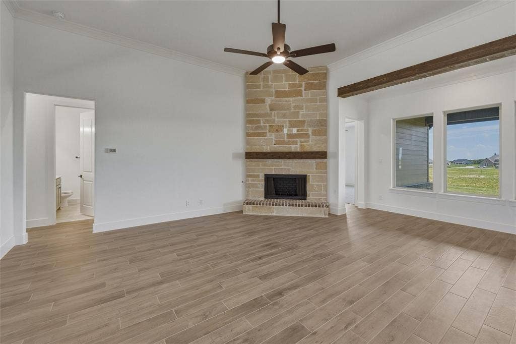 2408 Quartz Street, Krum, TX 76249 Spacious living area featuring a stone-clad fireplace with a wood mantel, wood-finish flooring, and multiple windows