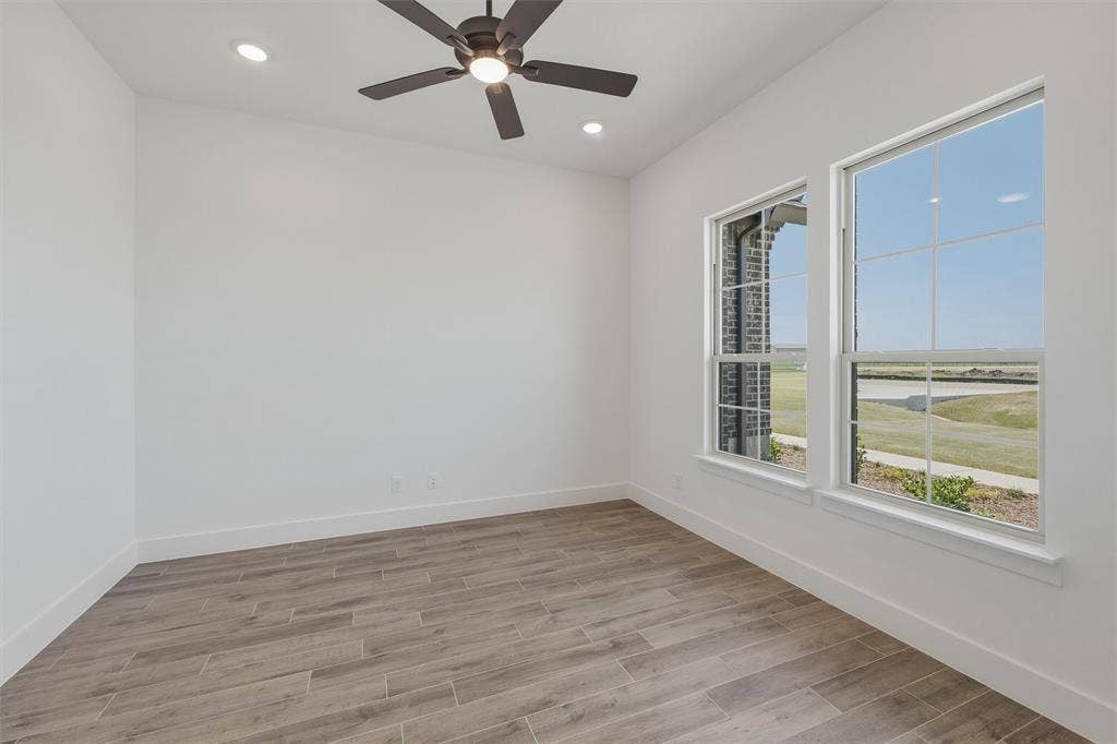 2408 Quartz Street, Krum, TX 76249 Bright room featuring two large windows with grid patterns, wood-finish flooring, a ceiling fan, and recessed lighting