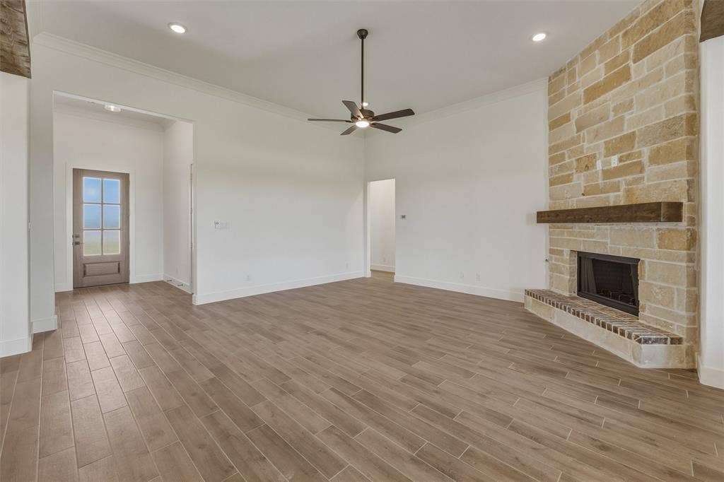 2408 Quartz Street, Krum, TX 76249 Spacious living area featuring plank-style tile flooring, a stone-clad fireplace with a wood mantle, and a ceiling fan