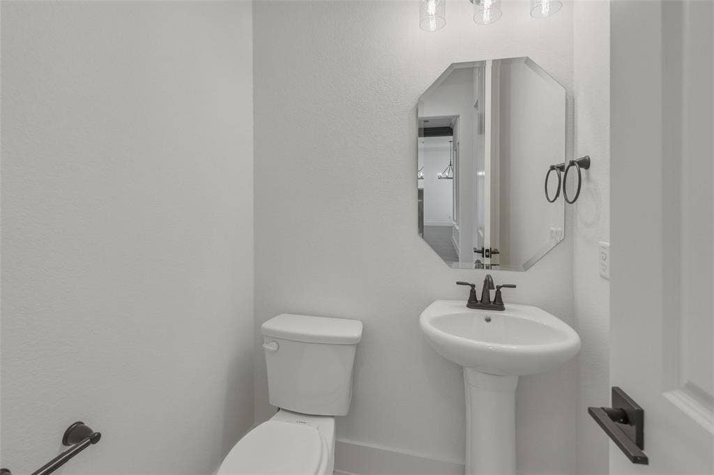 2408 Quartz Street, Krum, TX 76249 Pedestal sink with black fixture and octagonal mirror